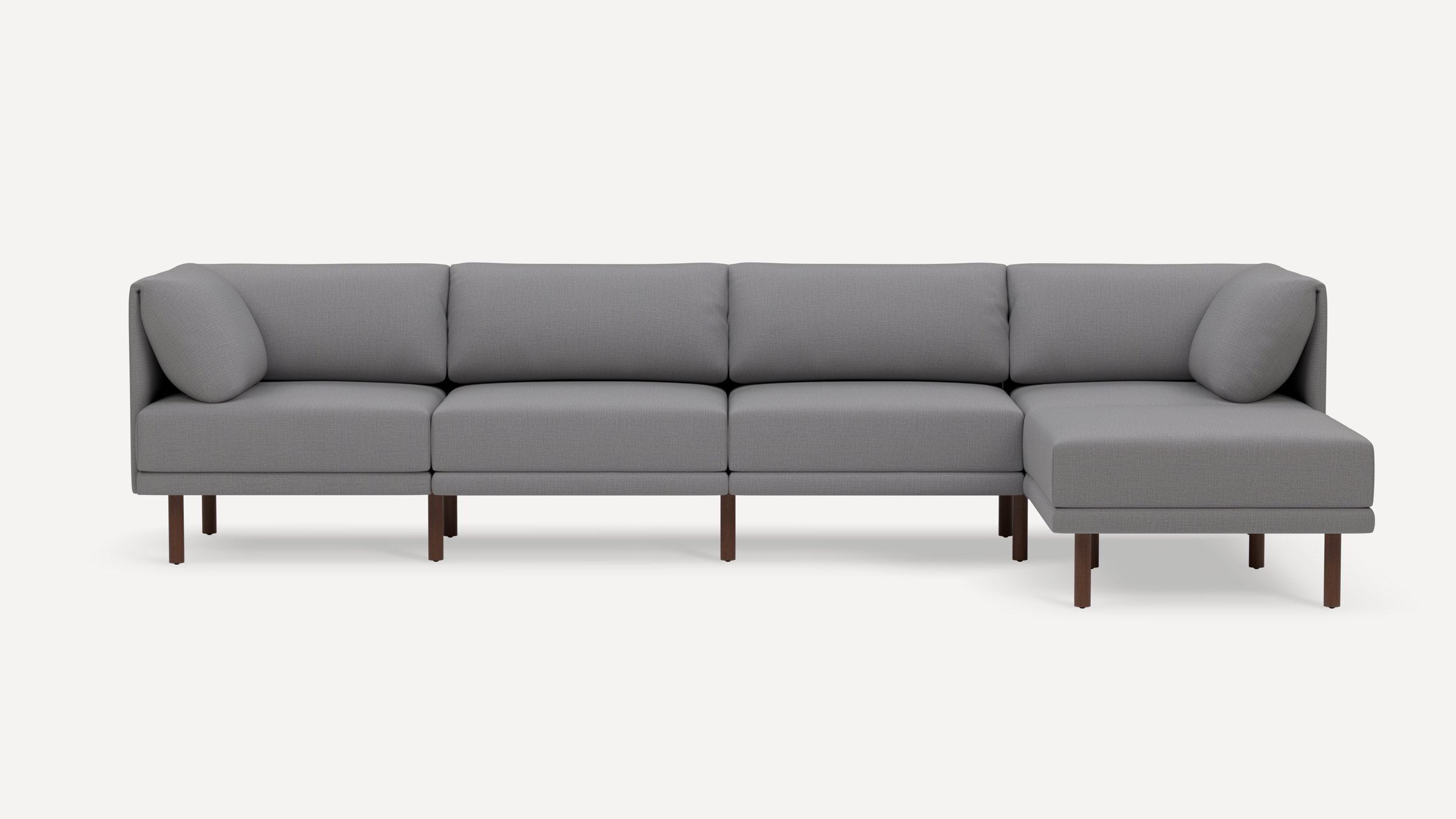 Modern gray fabric sectional sofa with wooden legs, featuring four seat cushions and two cylindrical arm pillows.