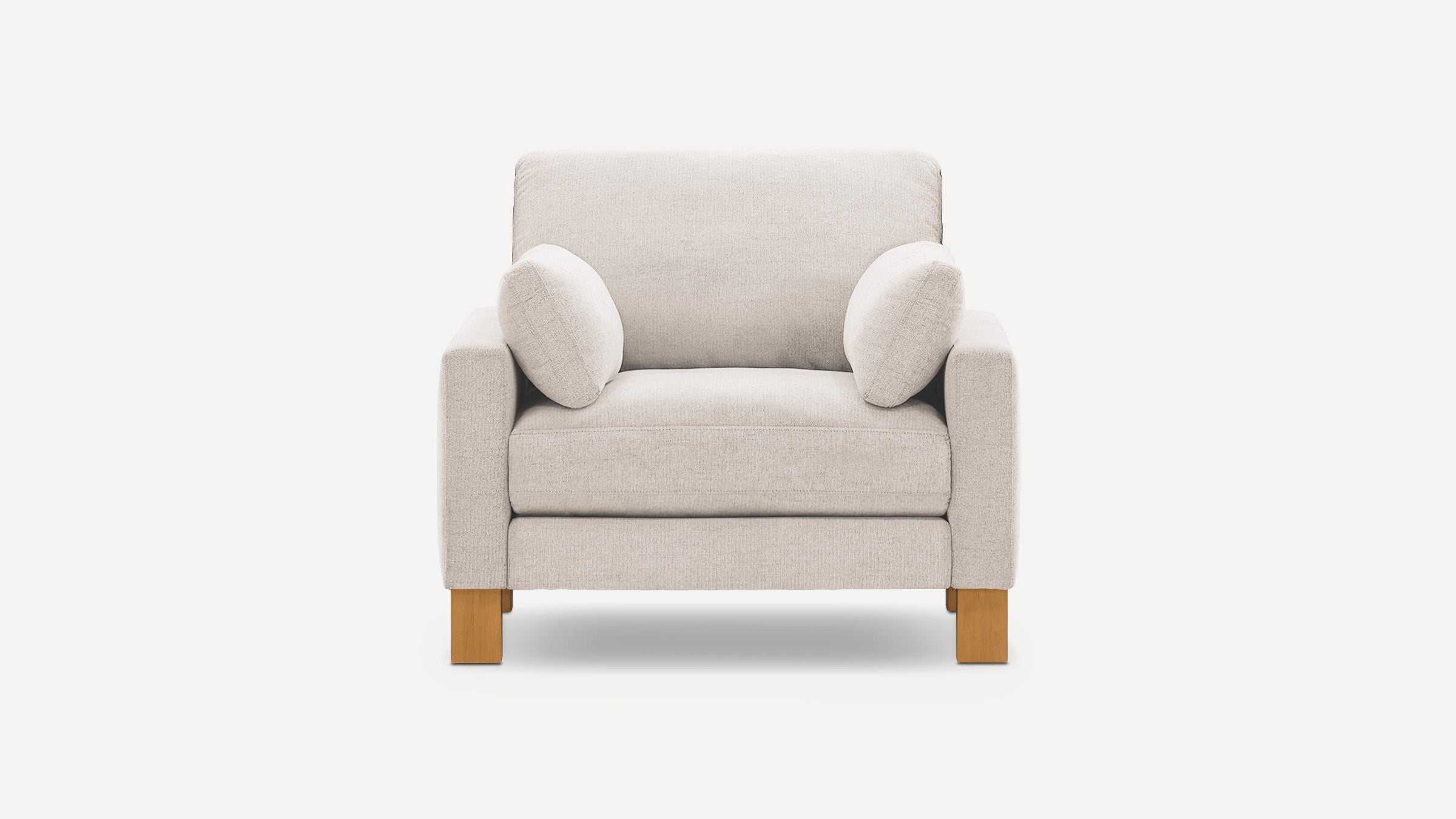 Front view of a beige upholstered armchair with square wooden legs and two small matching pillows.