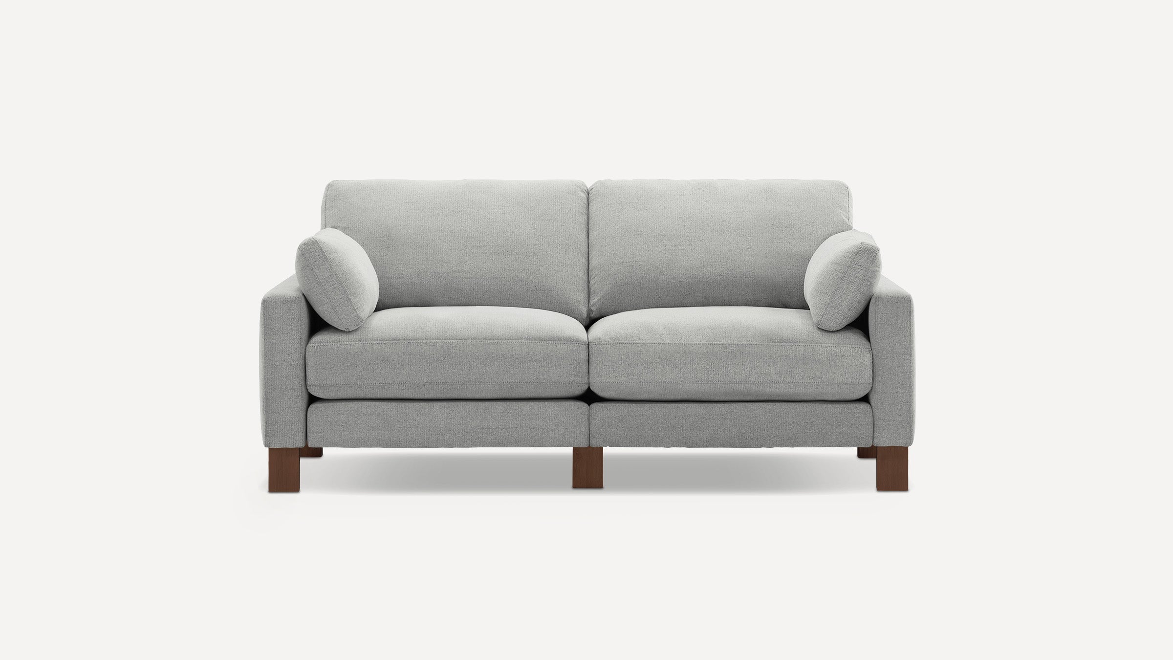 Light gray modern fabric loveseat sofa with square arms, two seat cushions, two round side pillows, and wooden legs.