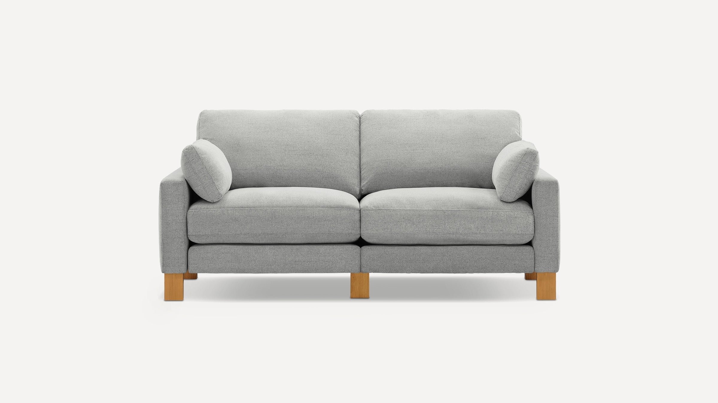 Light gray modern two-seater sofa with wooden legs and two matching cylindrical side cushions on a white background.
