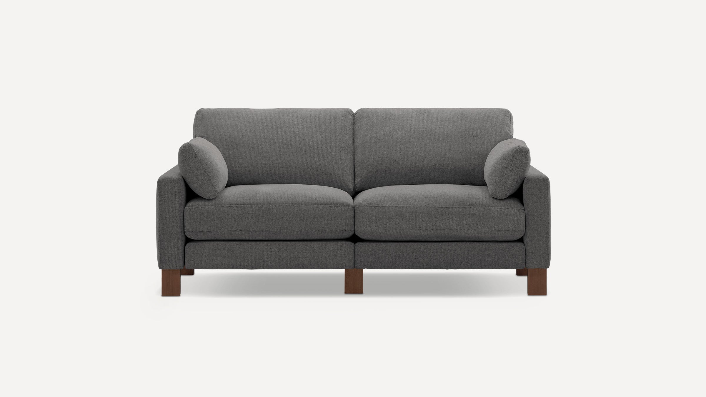 Modern dark gray upholstered two-seater sofa with wooden legs and two matching cylindrical side pillows.