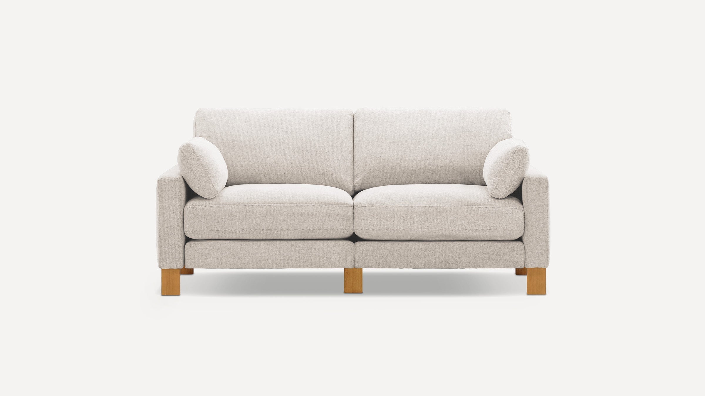 Light gray fabric two-seater sofa with wooden legs, thick cushions, and two matching cylindrical bolster pillows on each armrest.