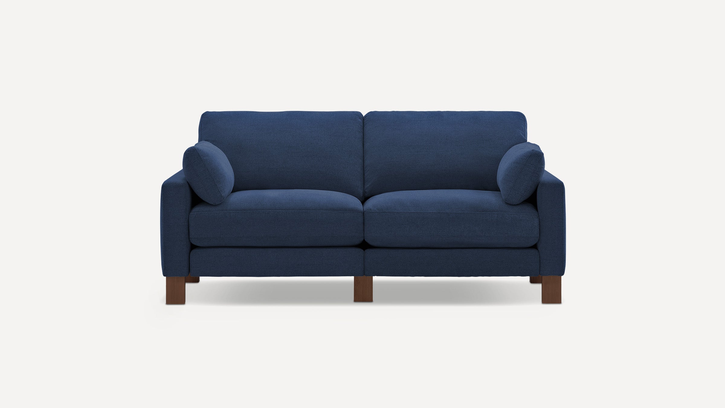 Modern navy blue fabric sofa with two seat cushions, two bolster pillows, and wooden legs on a white background.