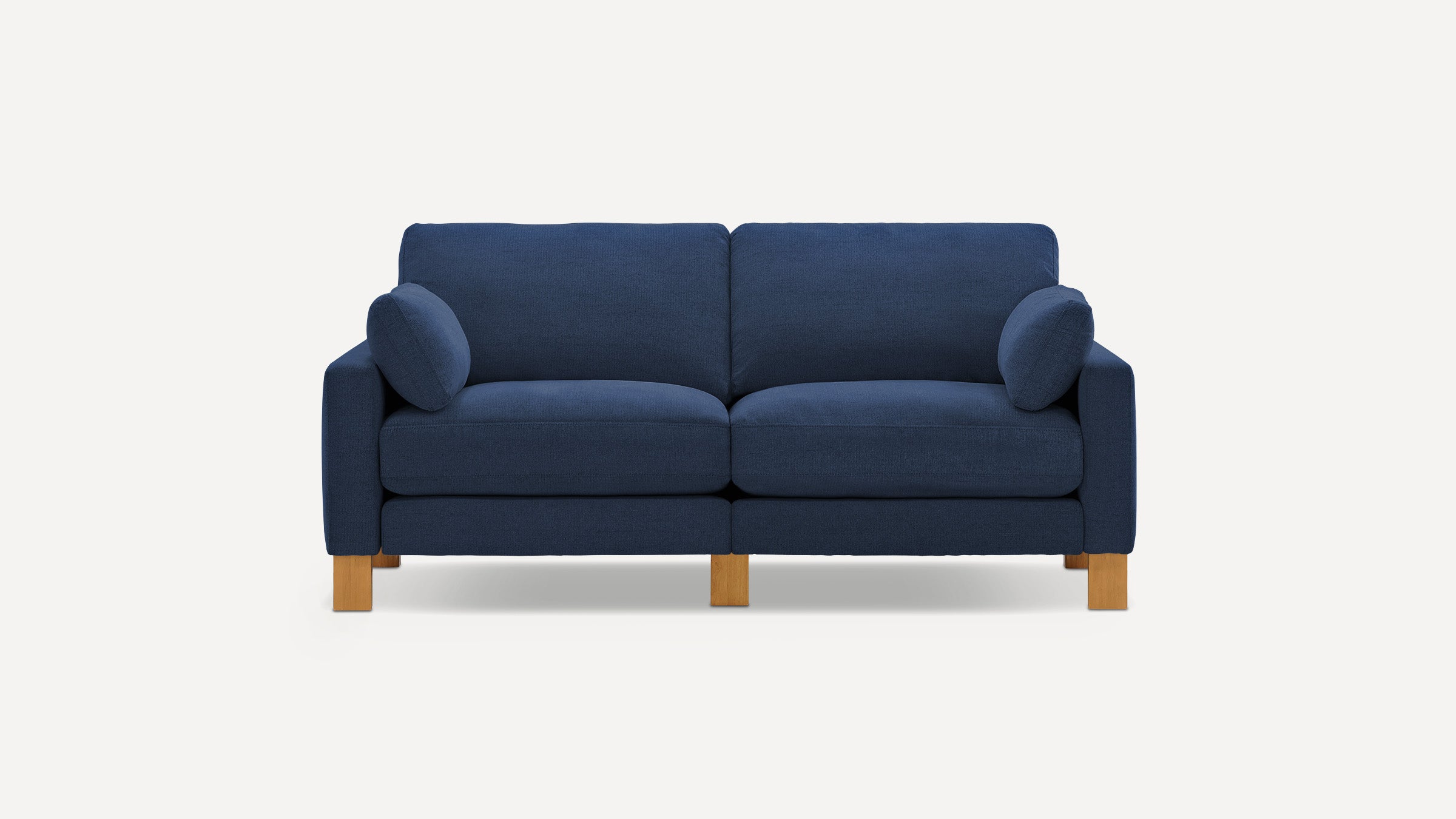 Modern navy blue fabric two-seater sofa with wooden legs and two matching cylindrical cushions on each armrest.