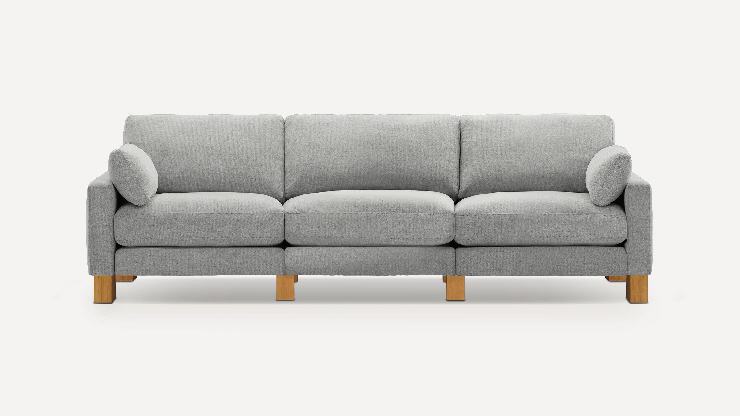 Modern three-seater sofa with light gray fabric upholstery, straight arms, wooden legs, and two round side pillows.