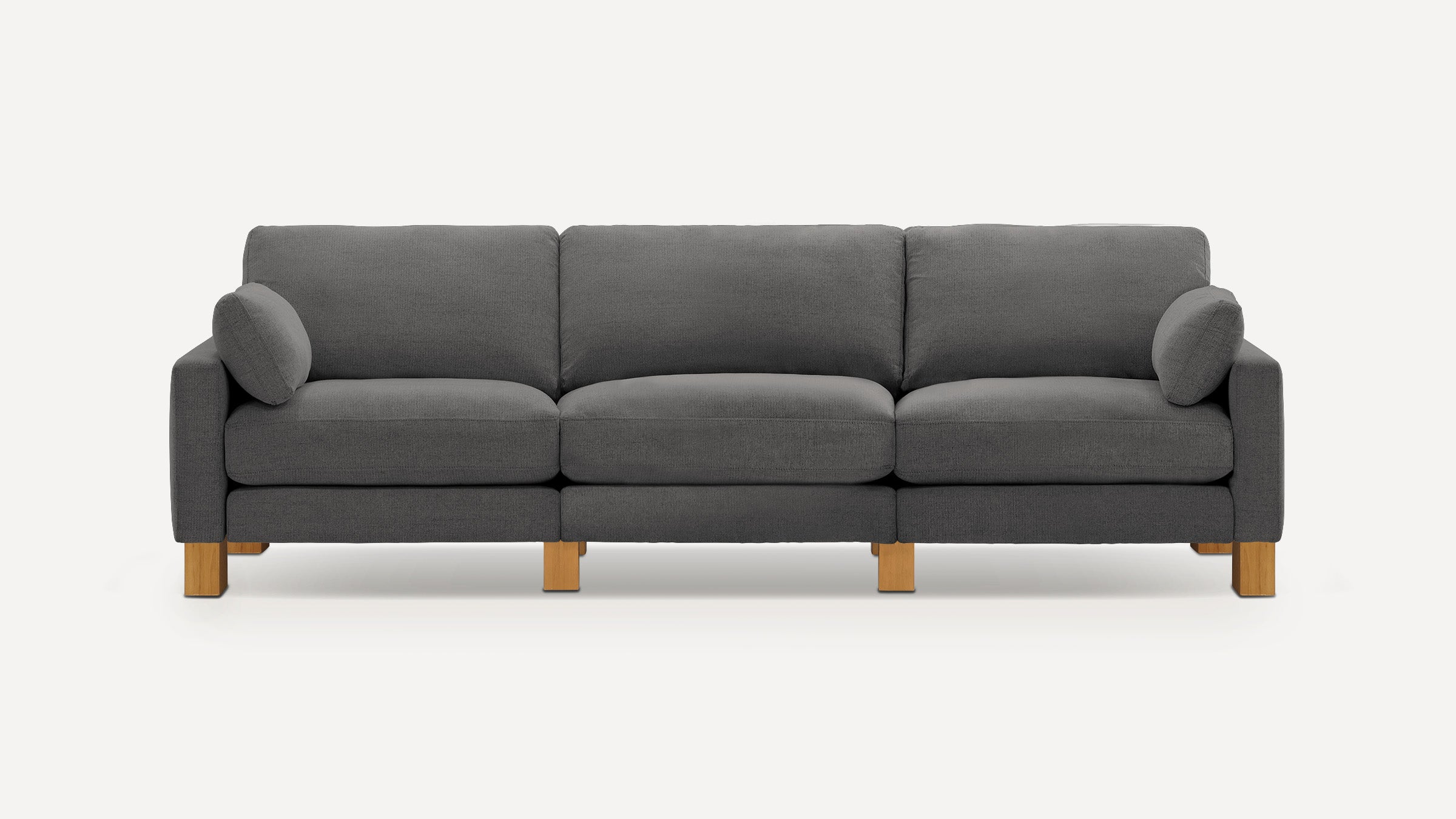 Modern three-seater sofa with dark gray fabric upholstery, wooden legs, and two matching side cushions against a plain background.