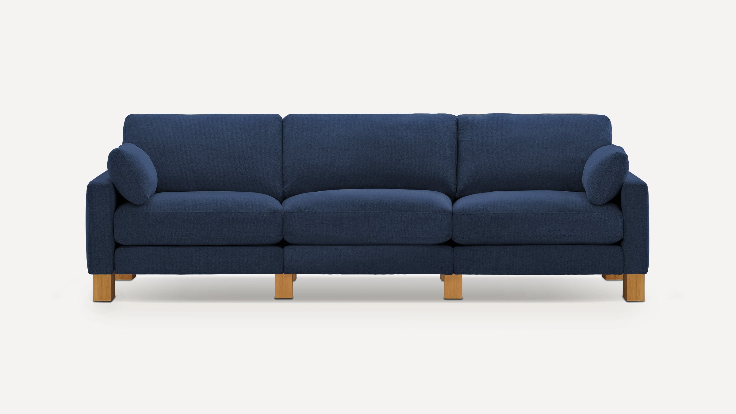 Modern three-seater sofa with deep blue fabric upholstery, wooden legs, and two matching cylindrical side cushions.