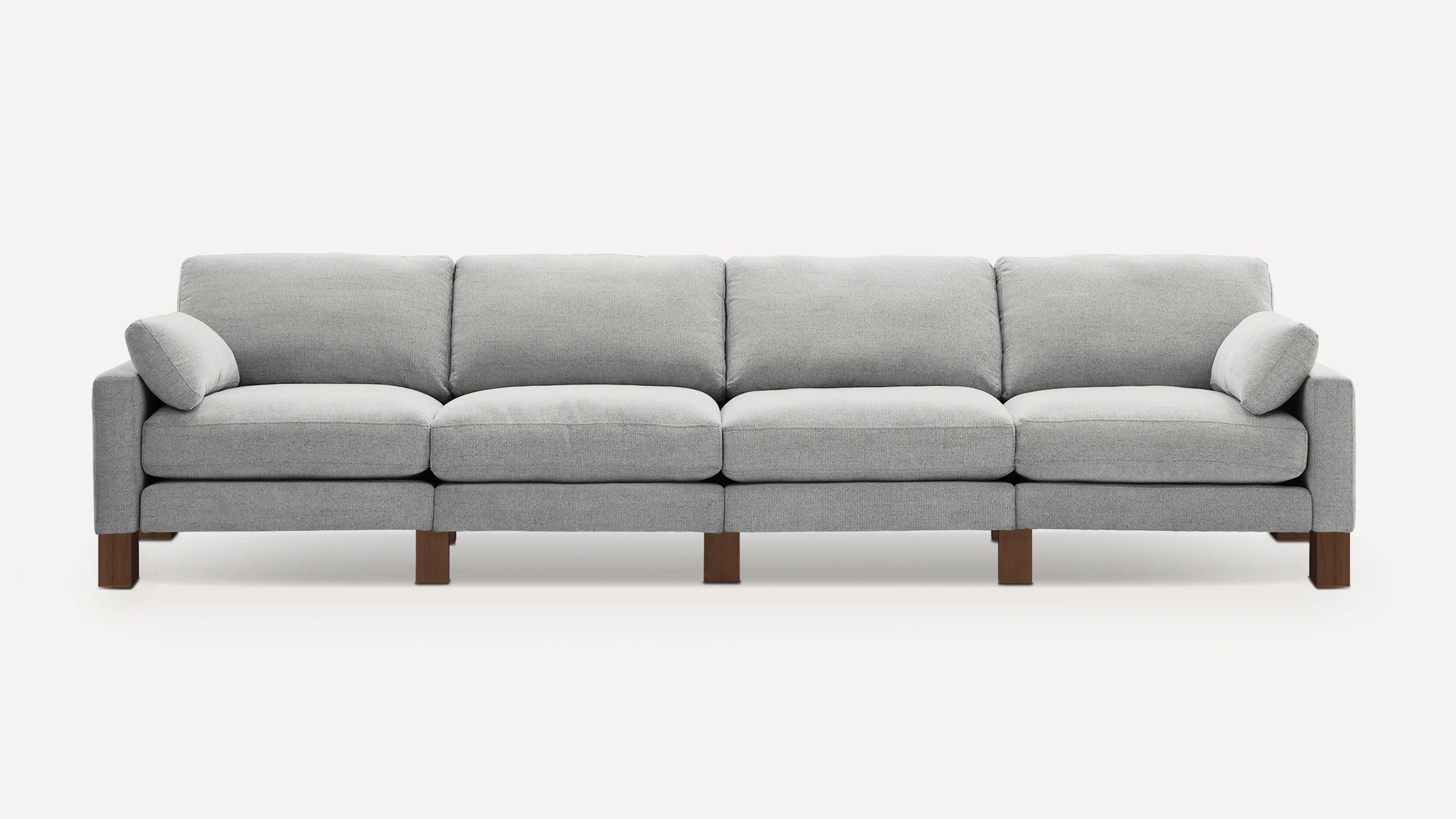 Modern light gray fabric sofa with four seats, rectangular cushions, two side pillows, and wooden block legs.