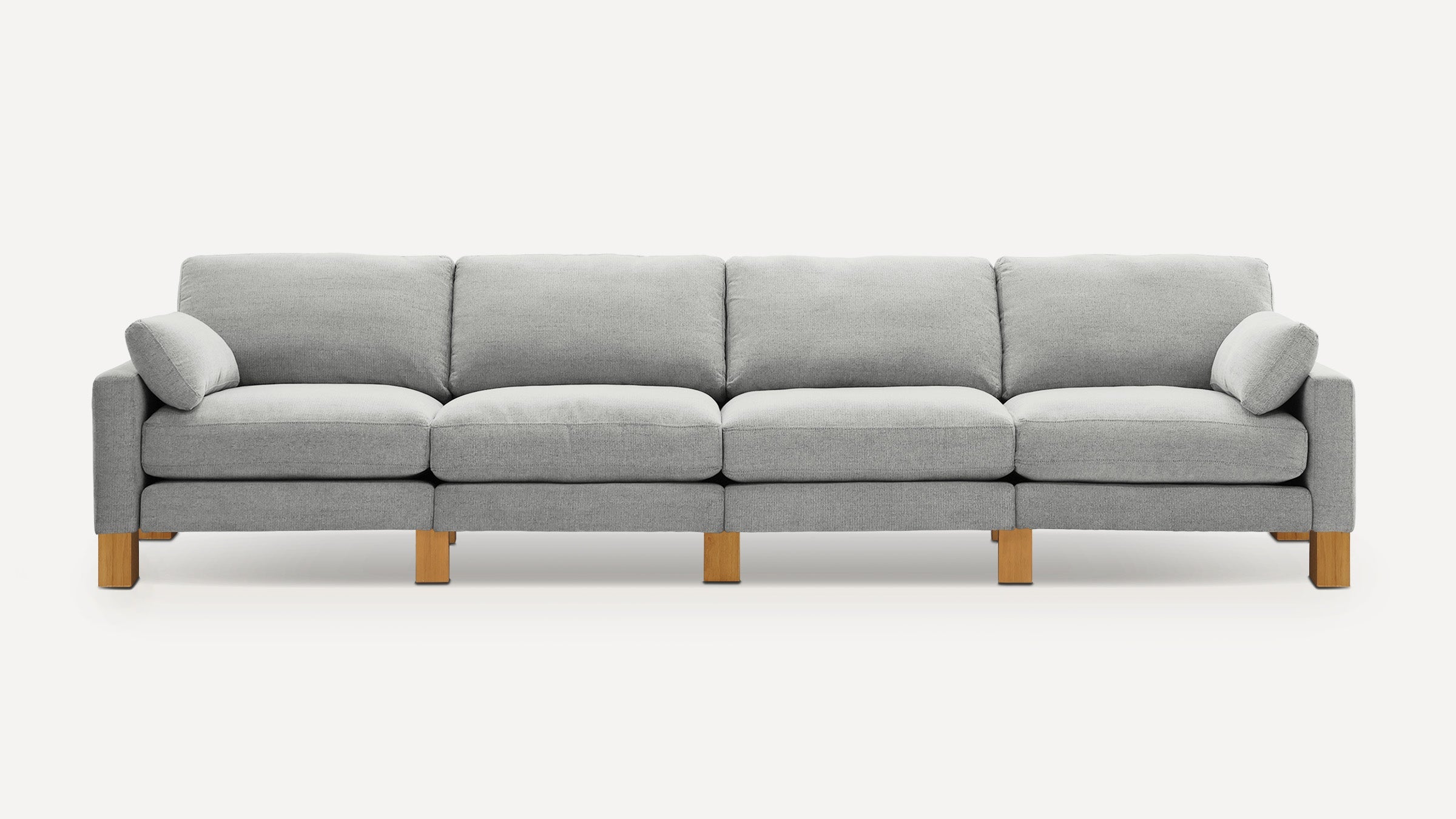 Modern light gray fabric sofa with four seat cushions, two matching arm pillows, and wooden block legs.