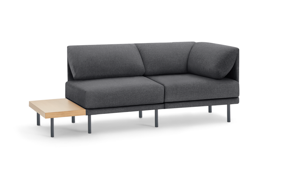 modern gray fabric sectional sofa with black metal legs and a wooden side table on a black background