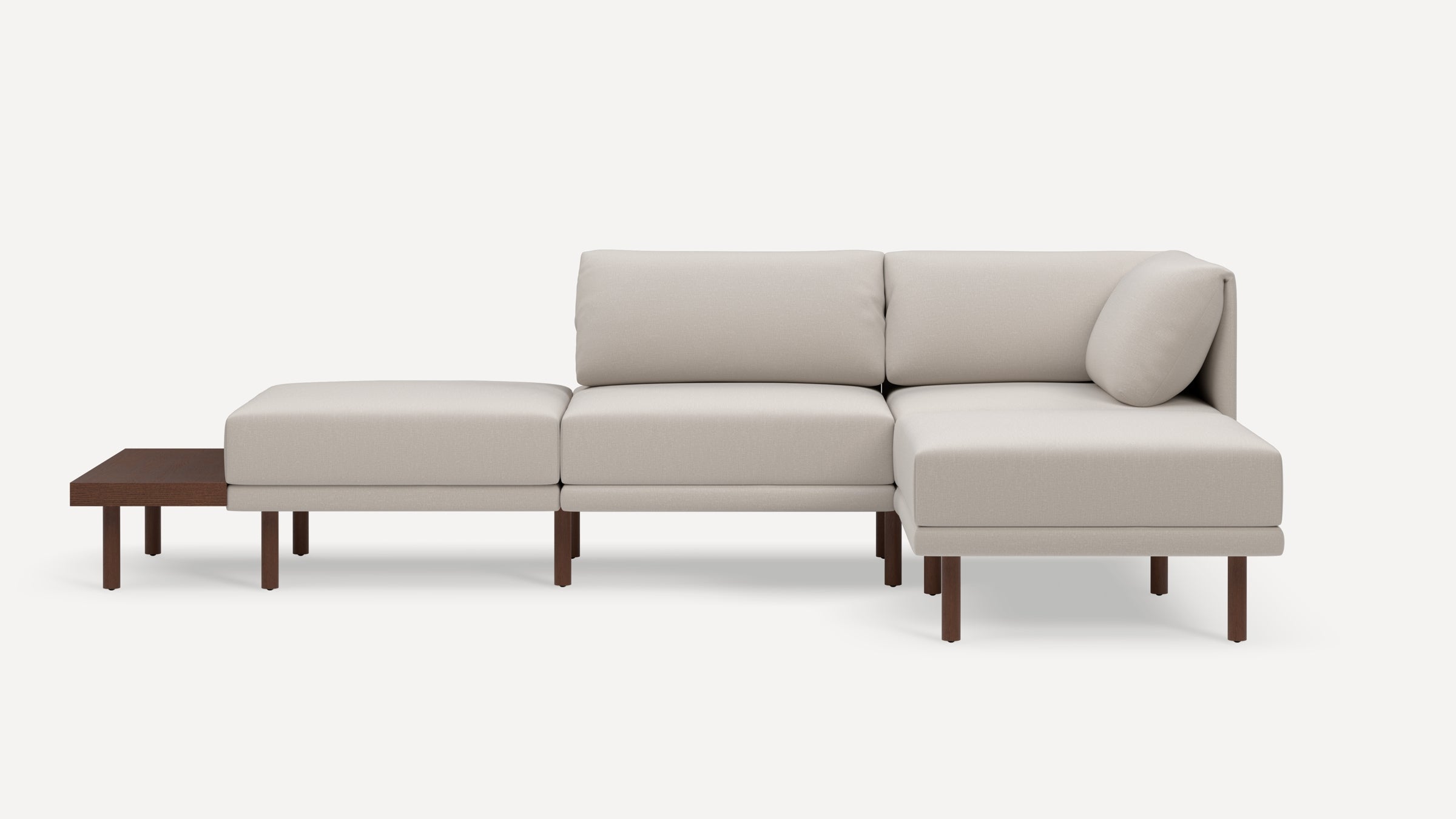 Modern beige sectional sofa with wooden legs, chaise lounge, and attached wooden side table on left side.