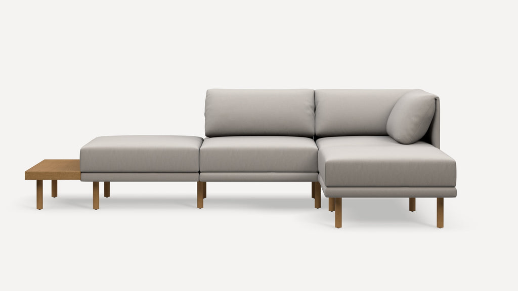 Modern light gray sectional sofa with right-side chaise, wooden legs, and an attached wooden side table extension.