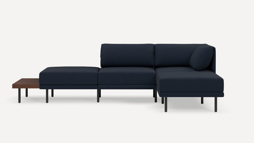 Modern navy blue sectional sofa with chaise lounge and minimalist black metal legs, featuring an attached wooden side table.
