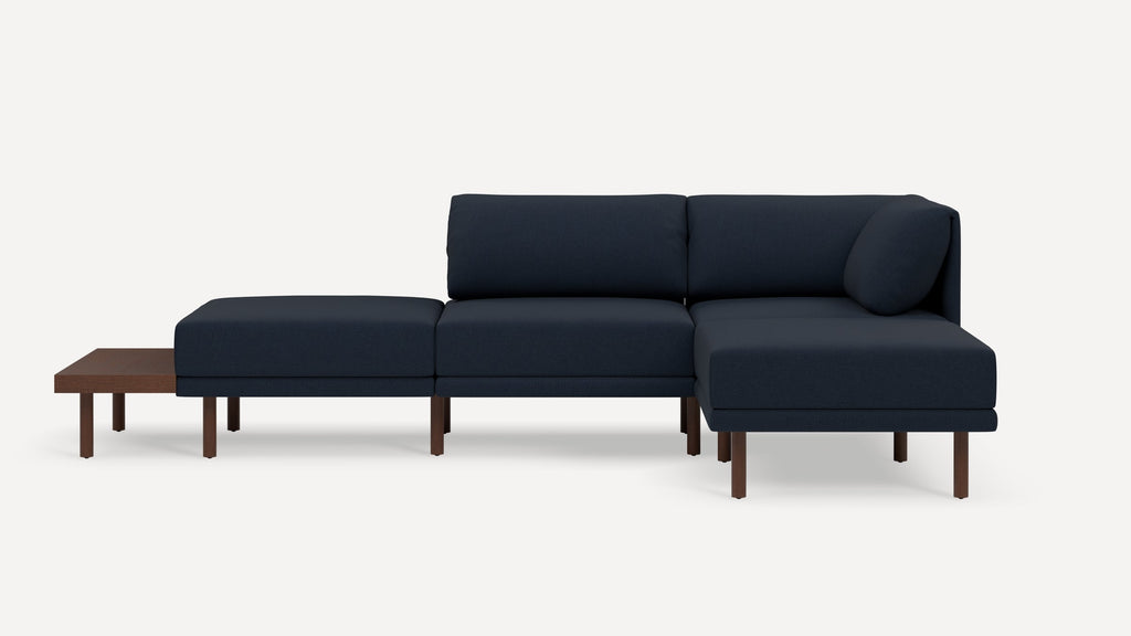 Modern navy blue sectional sofa with wooden legs and built-in side table on left end.