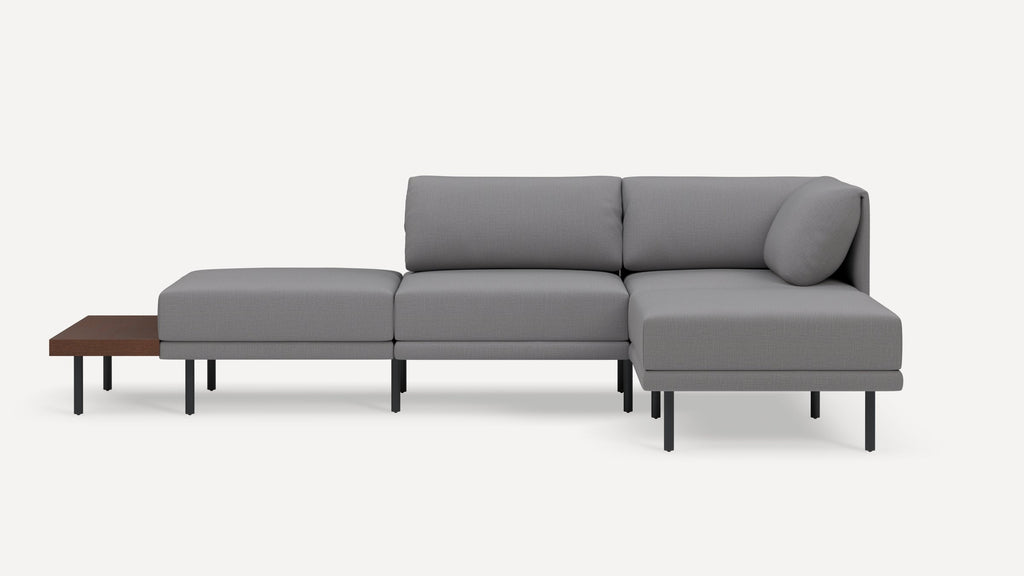 Modern gray sectional sofa with clean lines, slim black legs, cushioned seats, backrest, and an attached wooden side table.