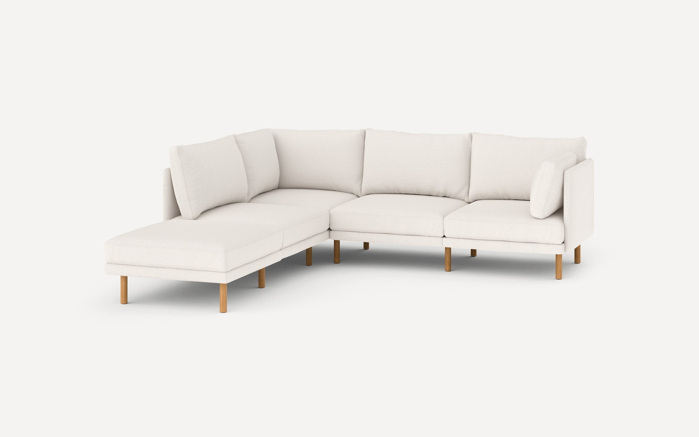 Modern L-shaped sectional sofa in white fabric with wooden legs, featuring cushioned seating and multiple back pillows.