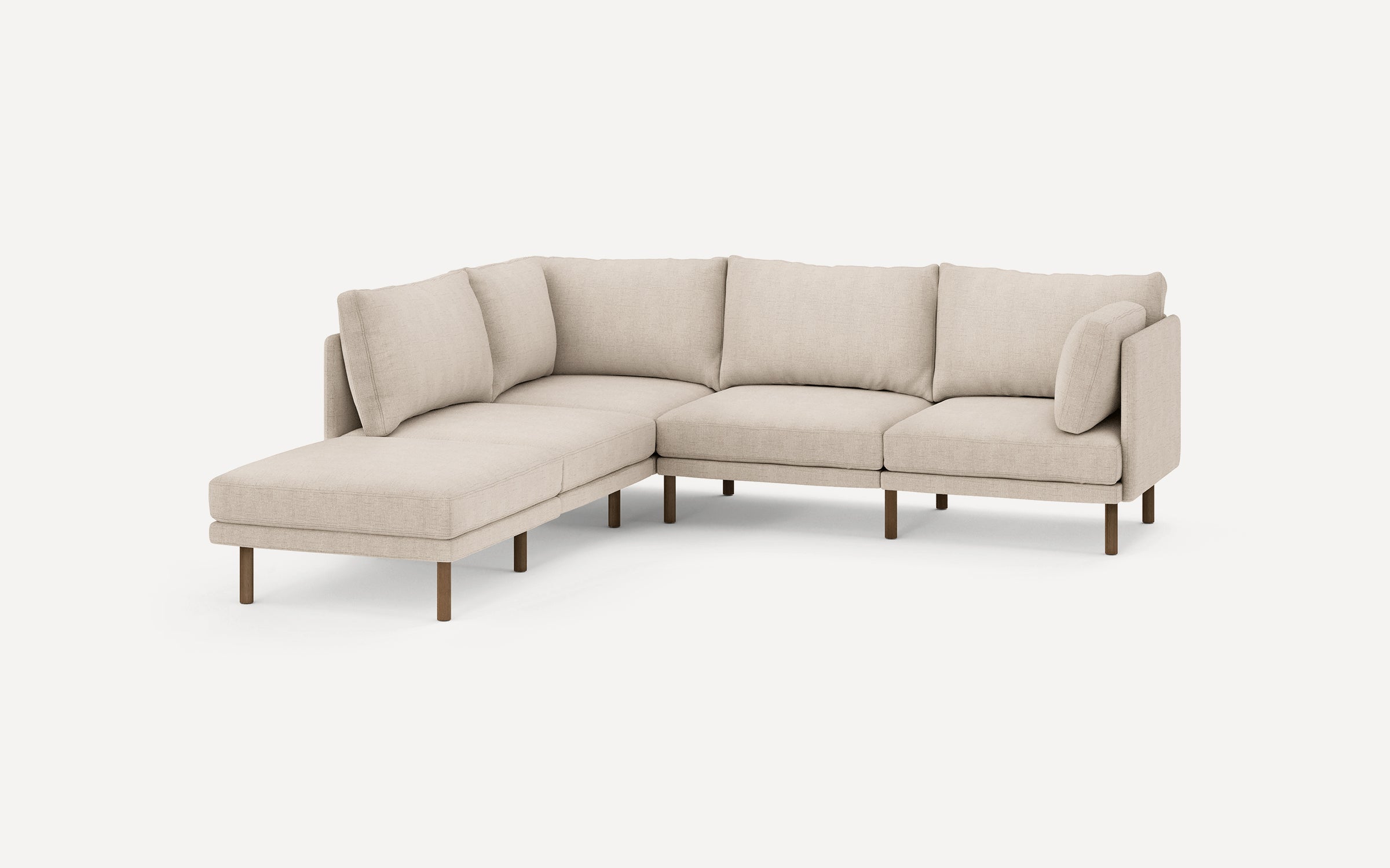 beige l - shaped sectional sofa with wooden legs and clean lines on the back, featuring a chaise lounge and matching ottoman