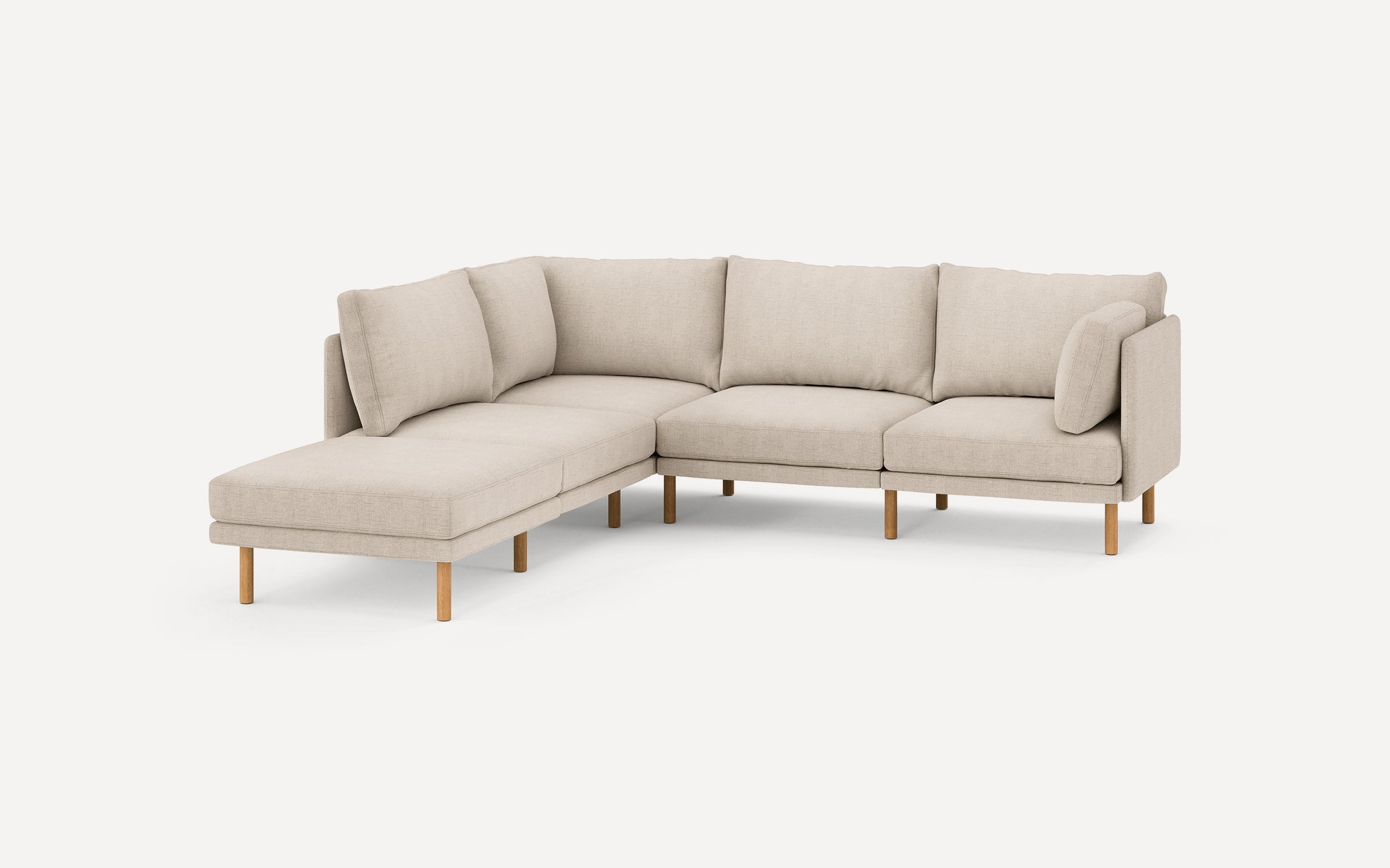 beige l - shaped sectional sofa with wooden legs and clean lines on the back, featuring a chaise lounge and matching ottoman