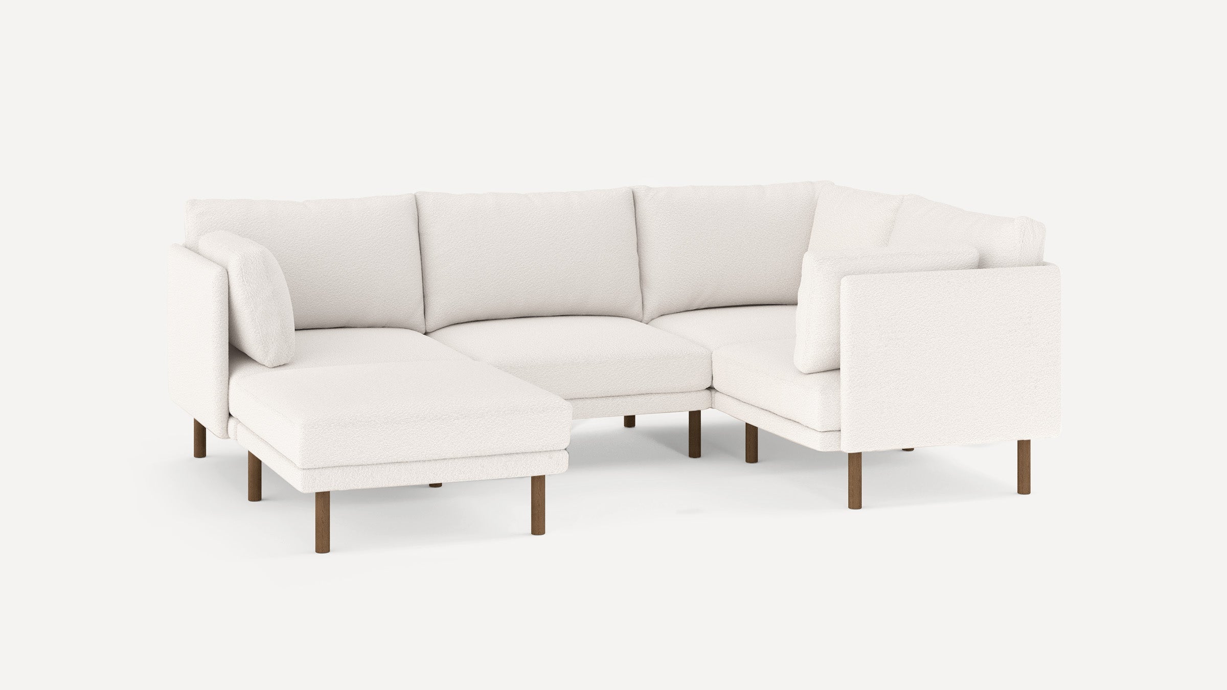 Modern white fabric sectional sofa with wooden legs, L-shaped design, cushioned back, and throw pillows.
