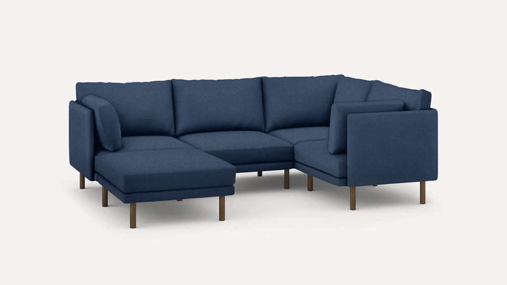 Modern navy blue sectional sofa with wooden legs, featuring a chaise lounge on the left side and cushioned backrests.