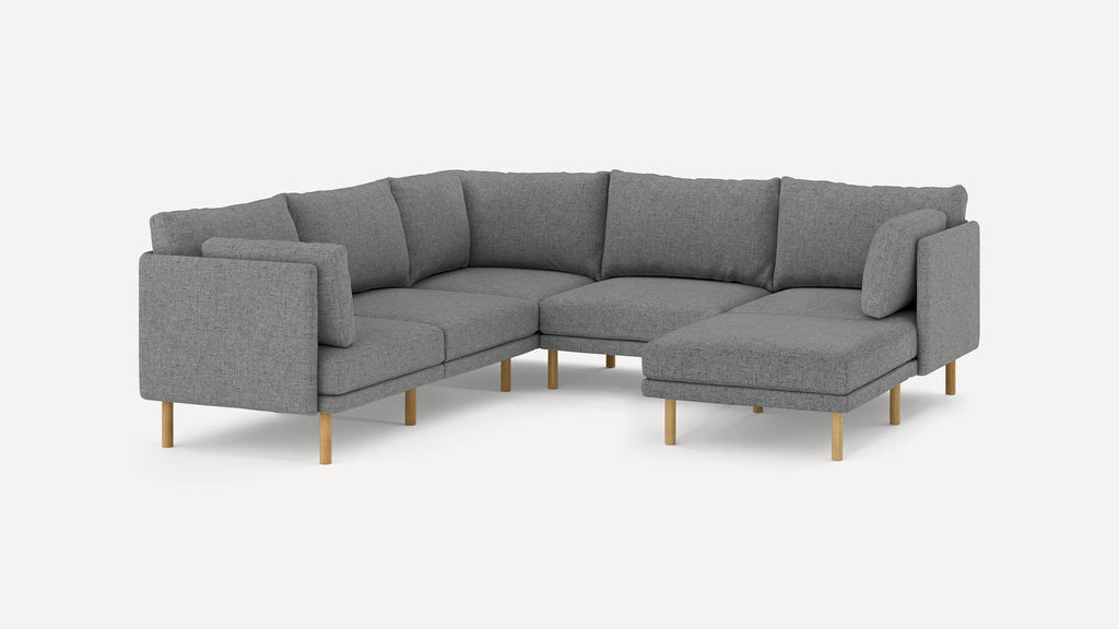Modern L-shaped sectional sofa with grey fabric upholstery, cushioned backrests, and light wooden legs against a plain white background.