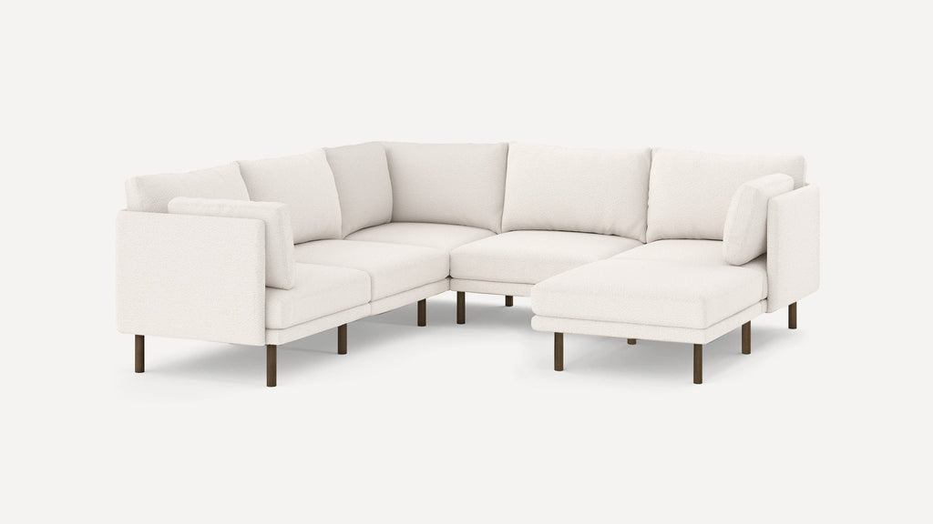 Modern L-shaped sectional sofa in white fabric upholstery with slim wooden legs and plush back cushions.
