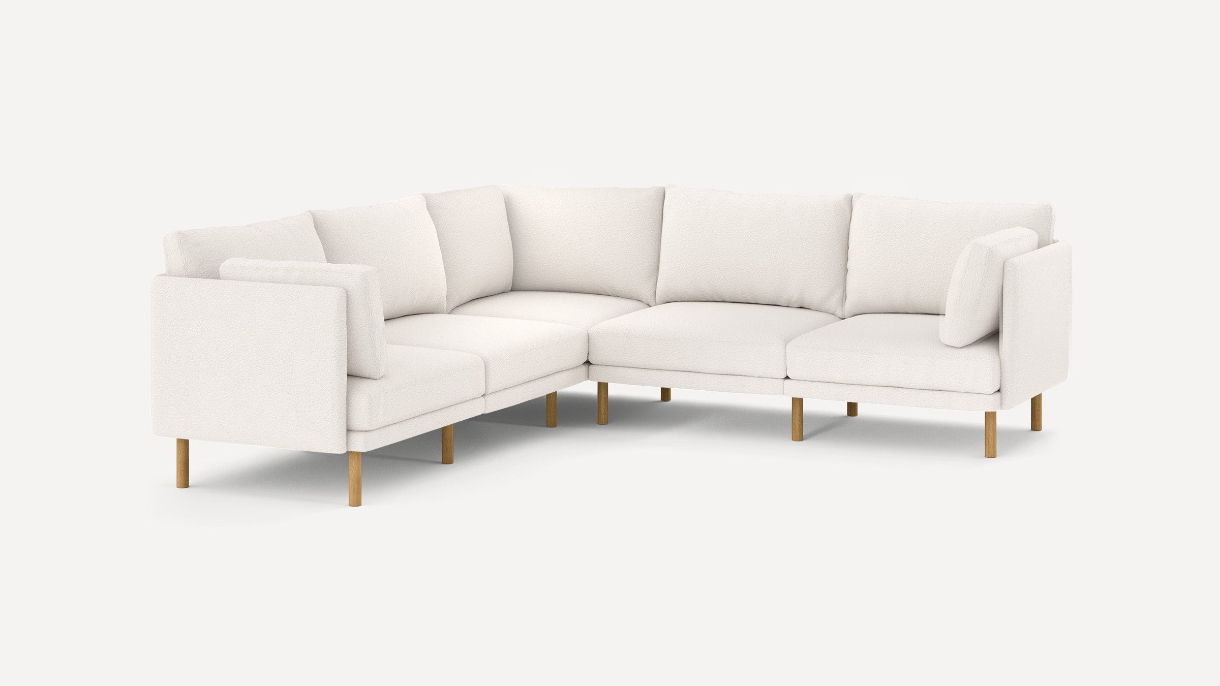 Modern L-shaped sectional sofa with cream-colored fabric upholstery and light wooden legs, featuring plush back and side cushions.