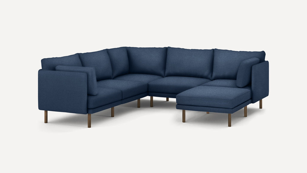 Modern L-shaped sectional sofa with deep blue fabric upholstery, cushioned seats, backrests, and wooden legs on a white background.