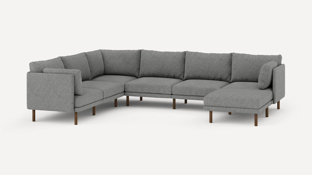 Modern L-shaped sectional sofa upholstered in gray fabric with wooden legs and multiple cushioned backs and seats.