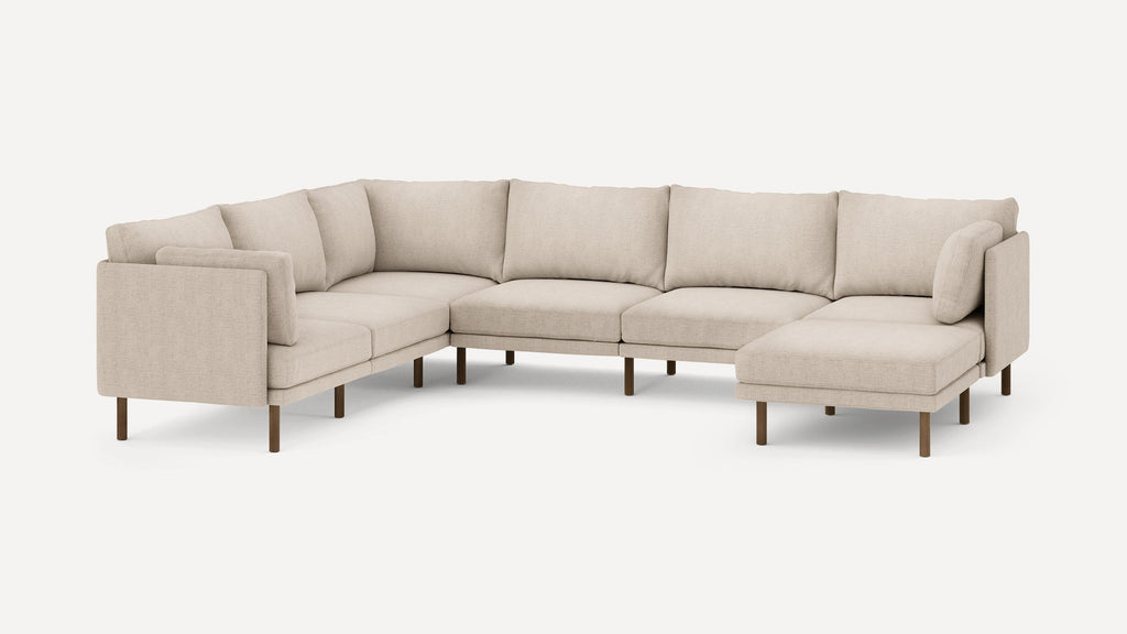 Beige fabric L-shaped sectional sofa with wooden legs and multiple cushions, offering spacious modern seating.