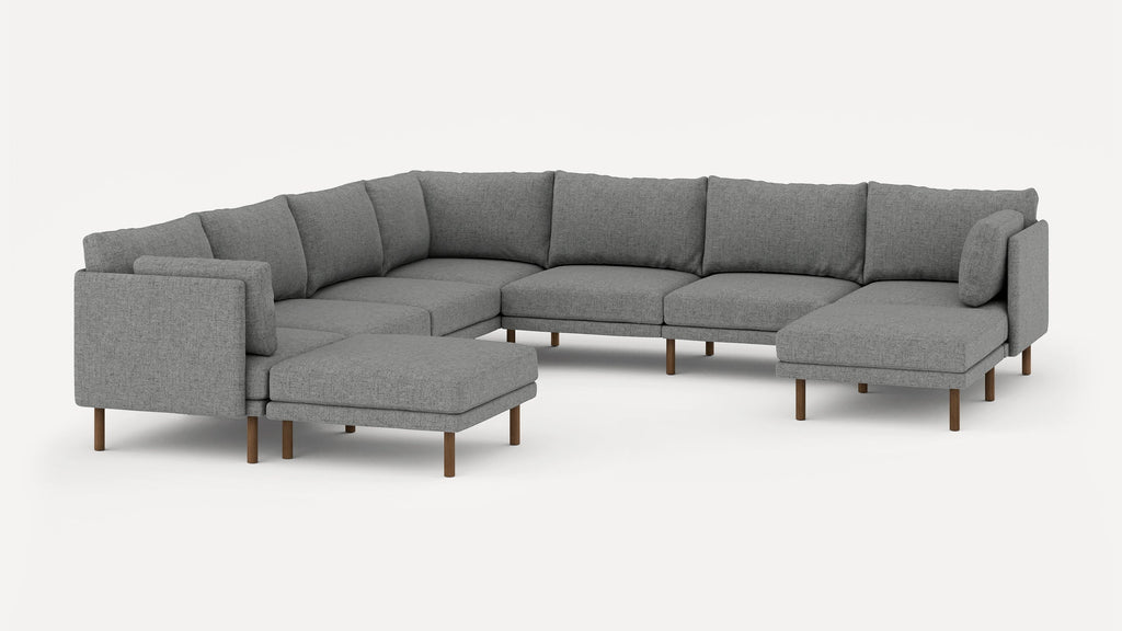Modern gray upholstered sectional sofa with wooden legs, including a matching ottoman and multiple cushions.