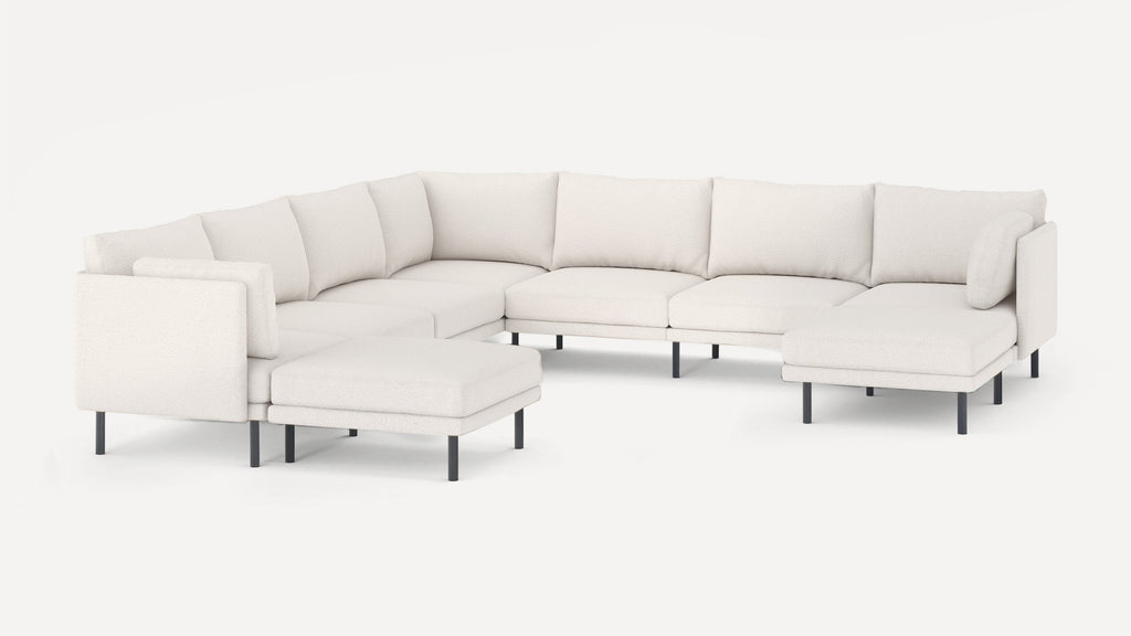 Large modern white sectional sofa with black metal legs, featuring multiple cushioned seats and backrests, including a chaise lounge and ottoman.