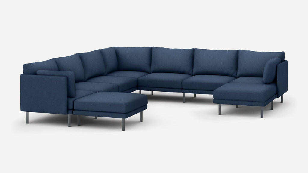 Large modern sectional sofa in dark blue fabric with metal legs, featuring multiple cushions and an extended chaise lounge on both ends.