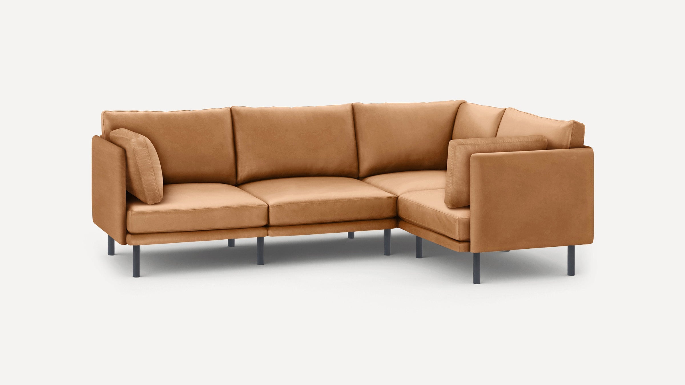 Modern L-shaped tan leather sectional sofa with slim metal legs and matching cushions on light background.