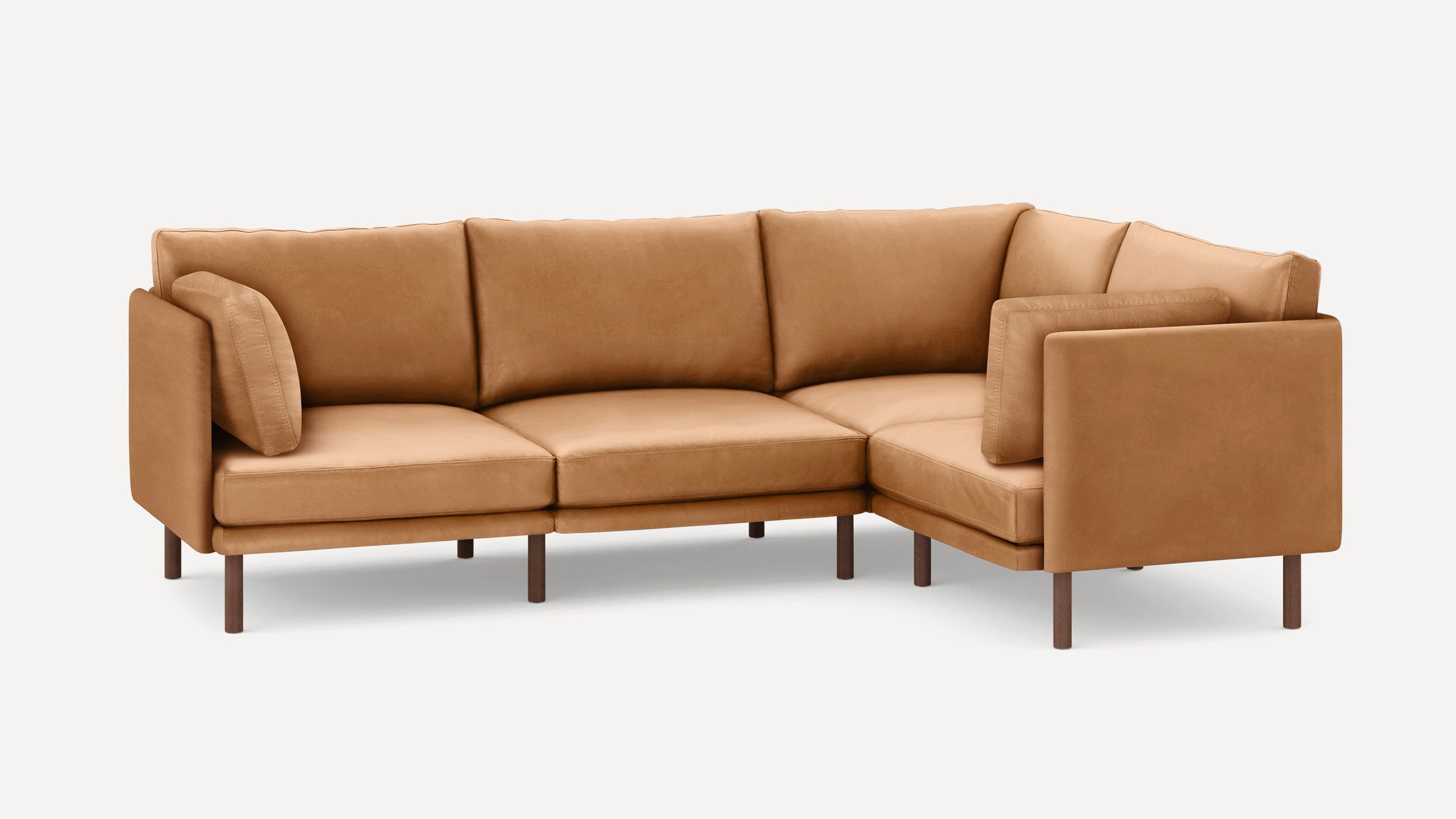 Modern L-shaped sectional sofa in tan leather upholstery with clean lines and dark wooden legs, featuring three seat cushions and backrest pillows.