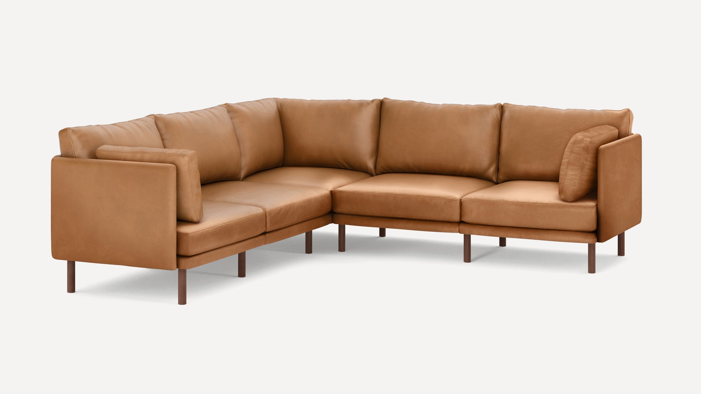 Modern L-shaped sectional sofa in tan leather with cushioned backrests and wooden legs, set against a white background.