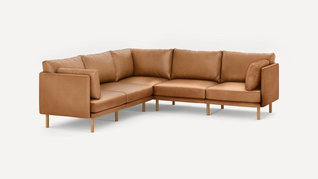 Modern L-shaped sectional sofa in tan leather with wooden legs and plush cushions, designed for spacious seating.