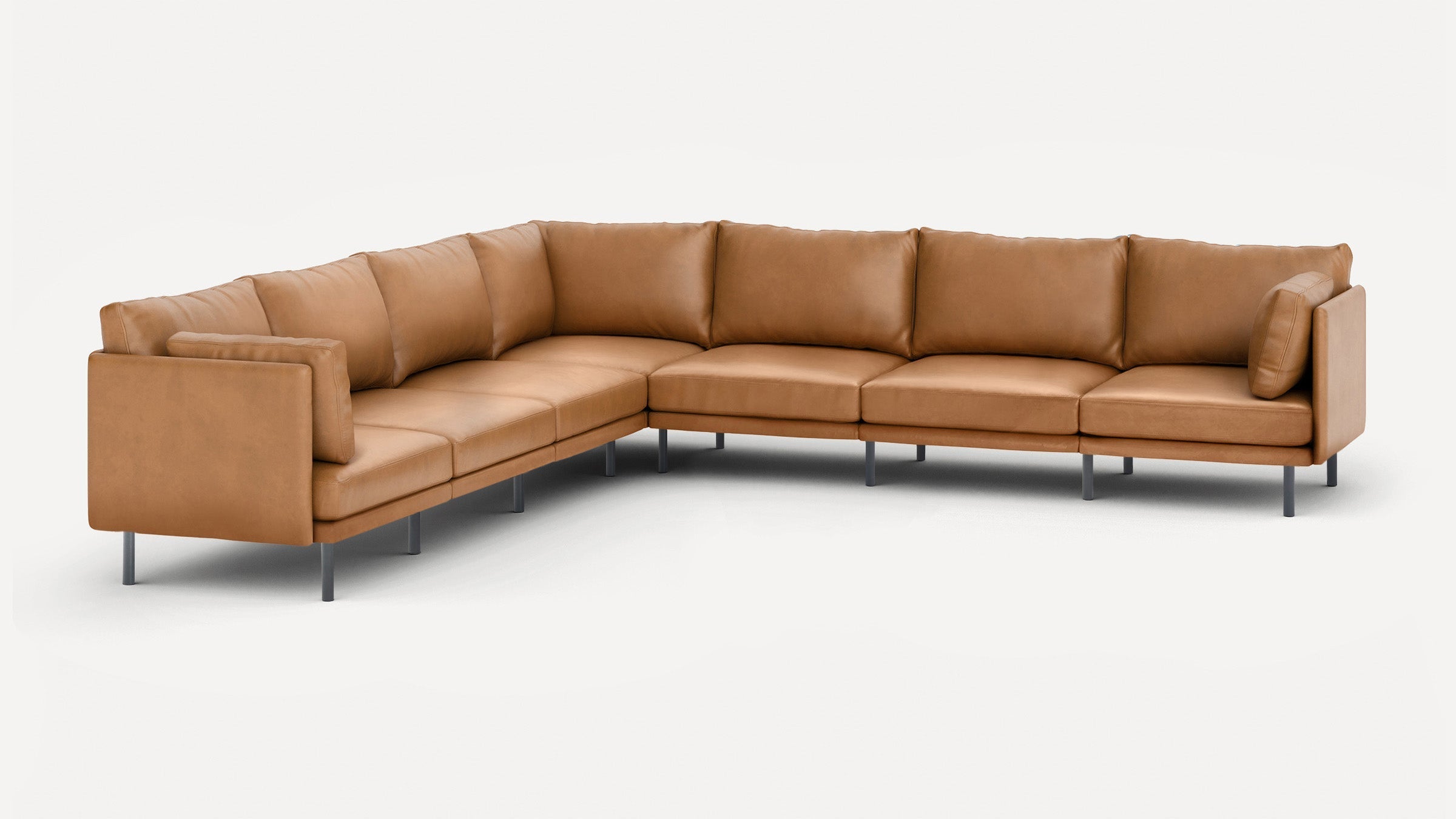 Large modern L-shaped sectional sofa in tan leather with slim metal legs and plush back and seat cushions.