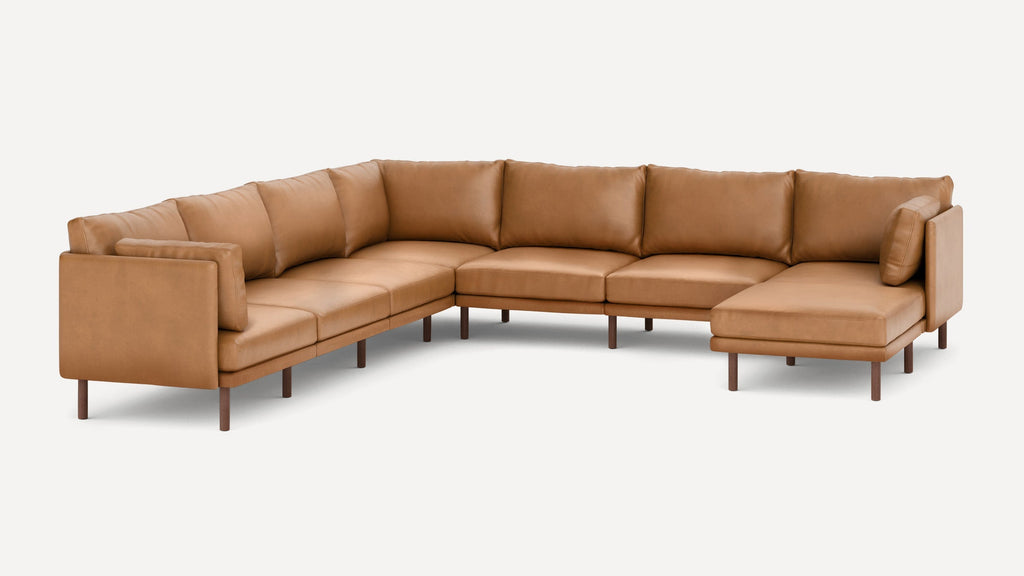 Modern L-shaped sectional sofa in tan leather with wooden legs and matching cushions, designed for spacious seating.