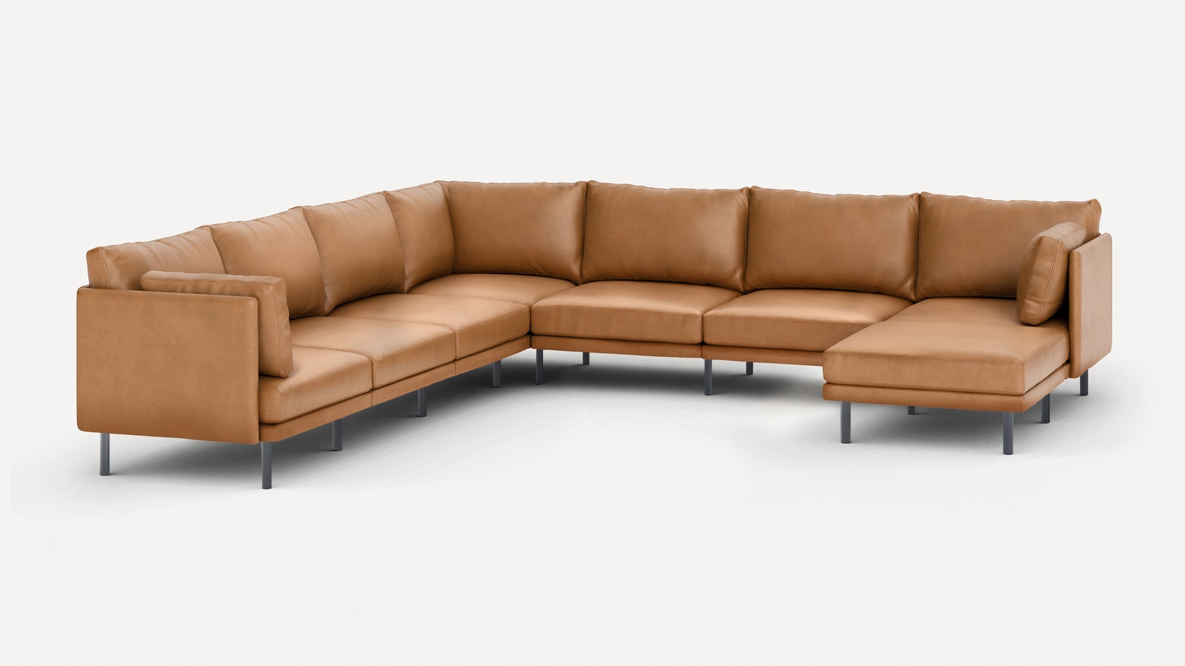 Large modern L-shaped sectional sofa with tan leather upholstery and metal legs, featuring plush cushions and a chaise lounge on one end.
