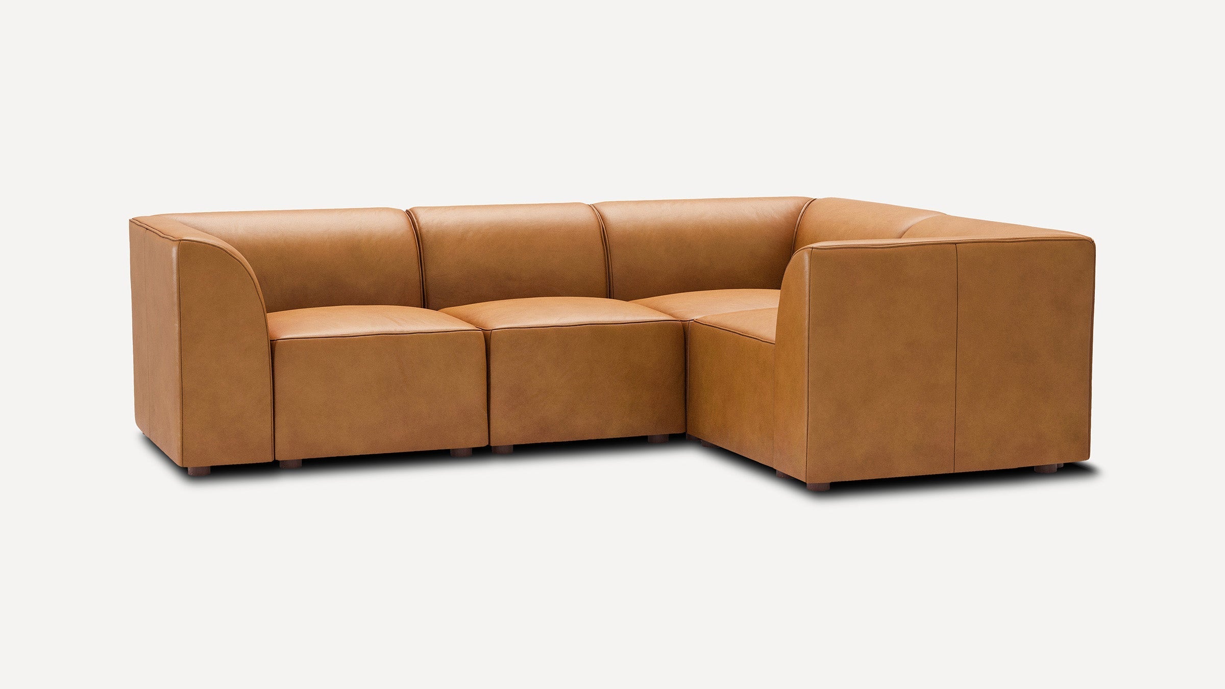 modern tan leather l - shaped sectional sofa with clean lines and rounded cushions, isolated against a white background