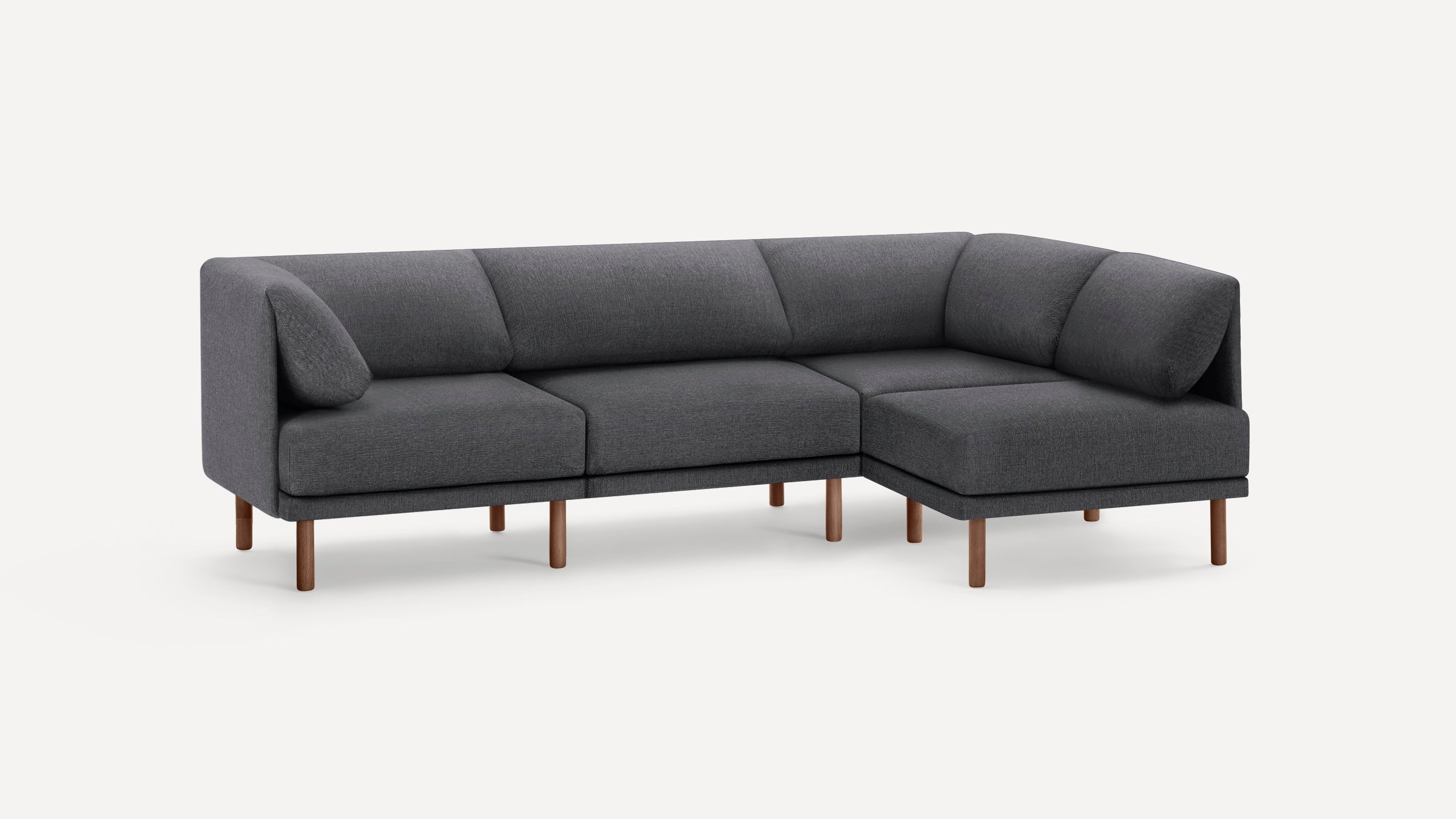 Modern L-shaped sectional sofa in dark gray fabric with wooden legs and plush back cushions on a white background.