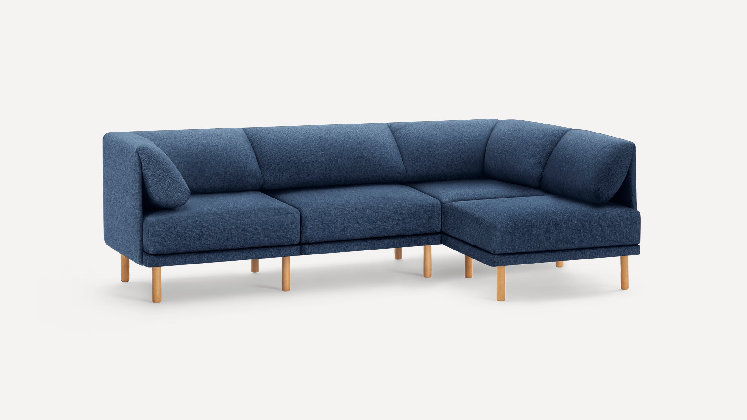Modern blue fabric sectional sofa with wooden legs, featuring a right-side chaise lounge and angled back cushions.