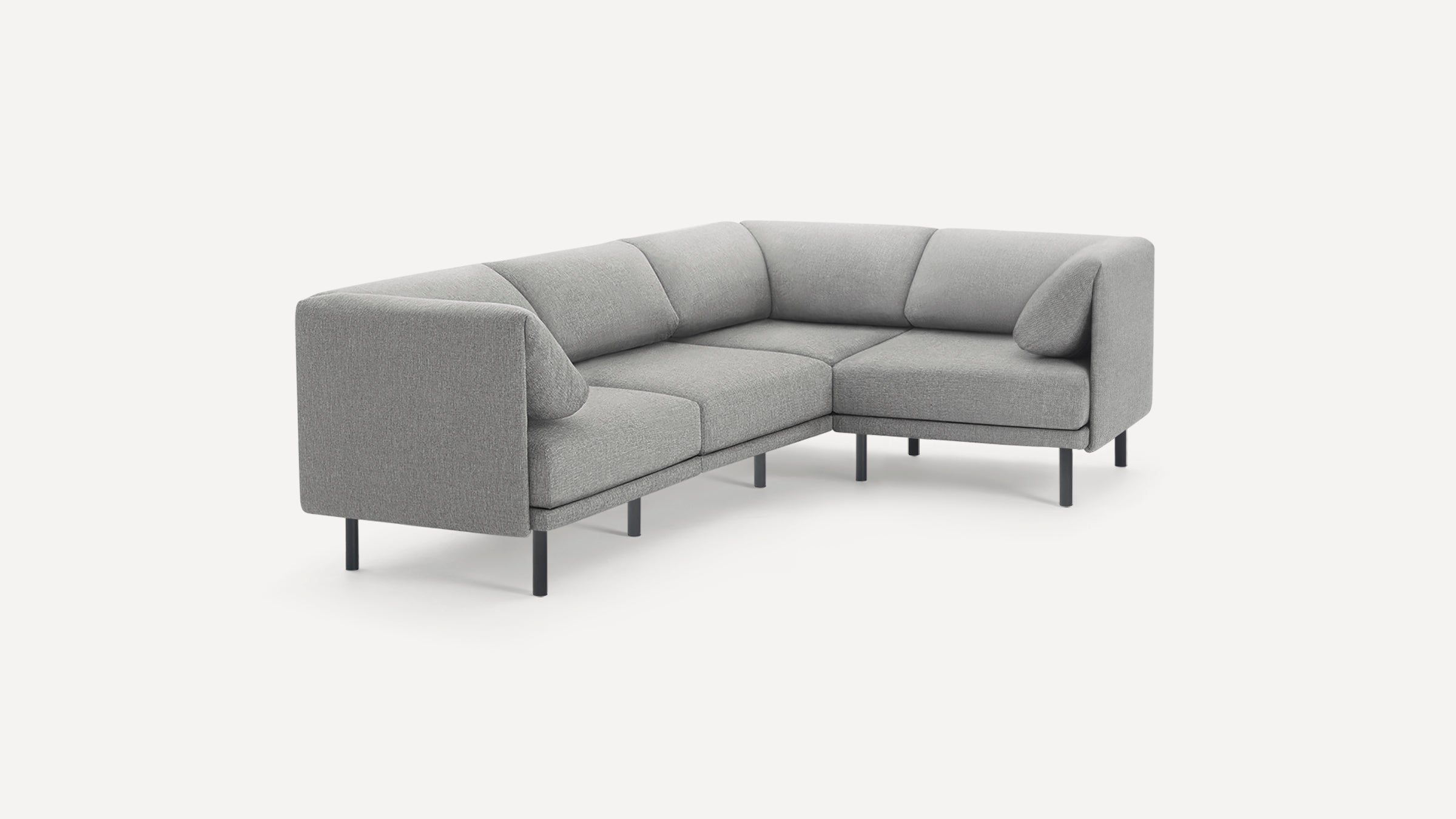 Modern L-shaped sectional sofa upholstered in light gray fabric with slim black legs and cushioned backrests.
