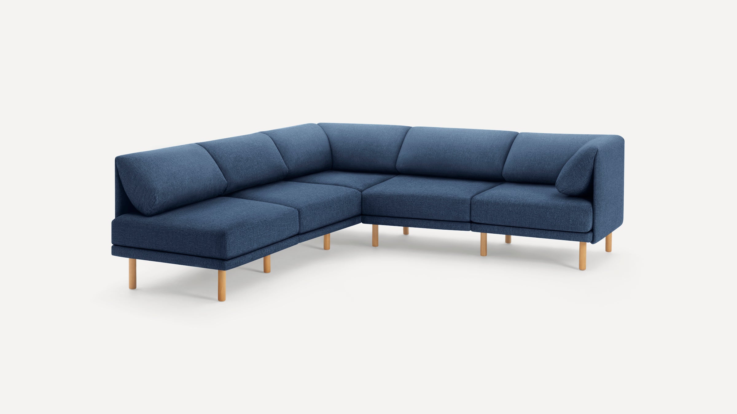 Modern L-shaped sectional sofa in navy blue fabric with wooden legs and plush back cushions on a white background.
