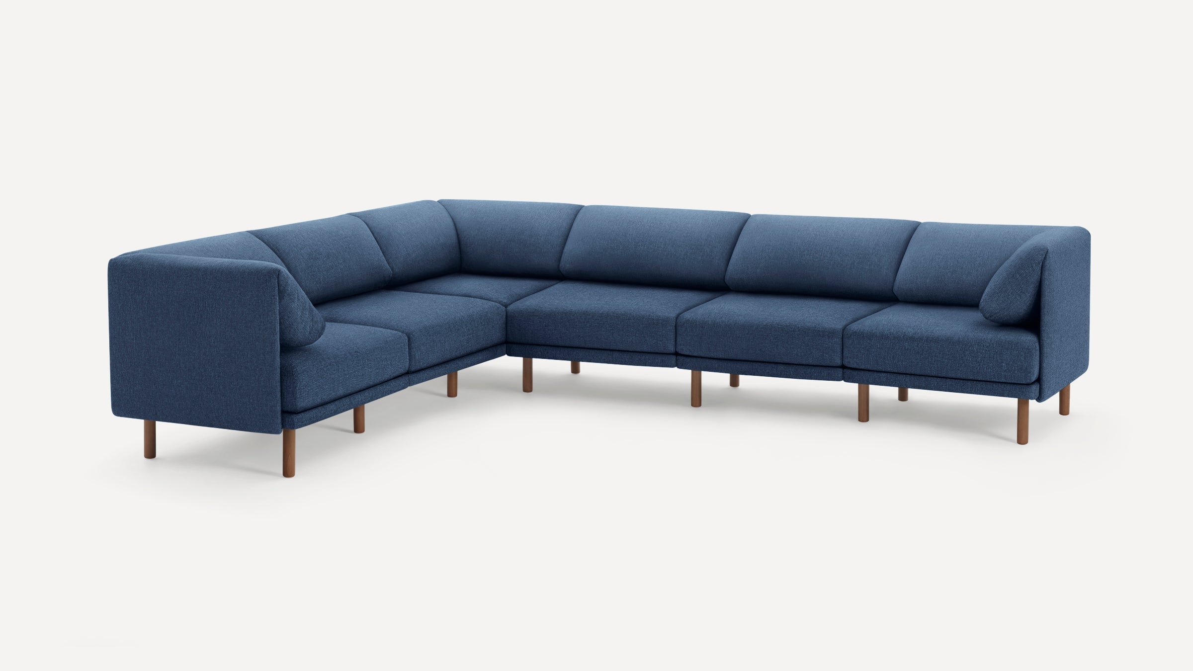 Modern L-shaped sectional sofa in blue fabric upholstery with wooden legs and two matching cushions, set against a white background.