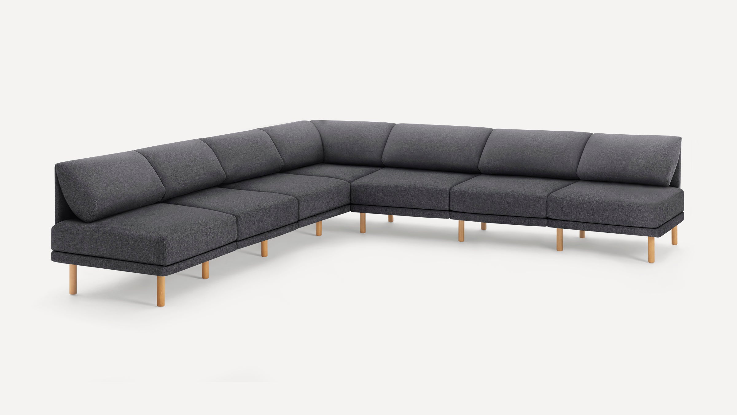 L-shaped modern sectional sofa with dark gray upholstery, low back cushions, and natural wooden legs on a white background.