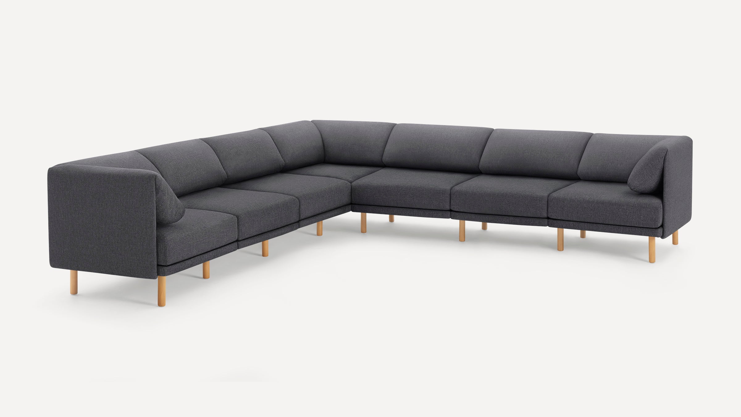 Large modern dark gray fabric sectional sofa with wooden legs and two matching corner pillows on a white background.