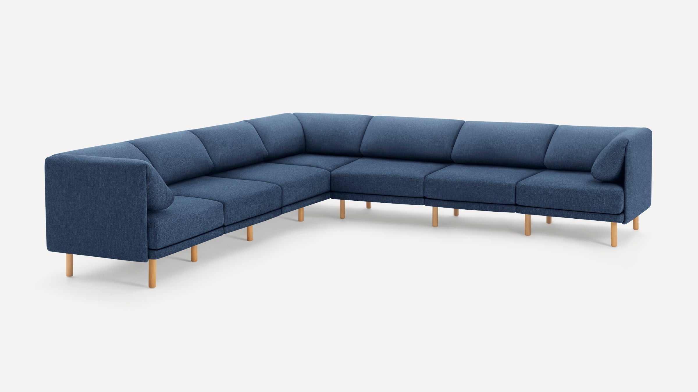 Large modern L-shaped sectional sofa in dark blue fabric with wooden legs, clean lines, and plush back cushions.