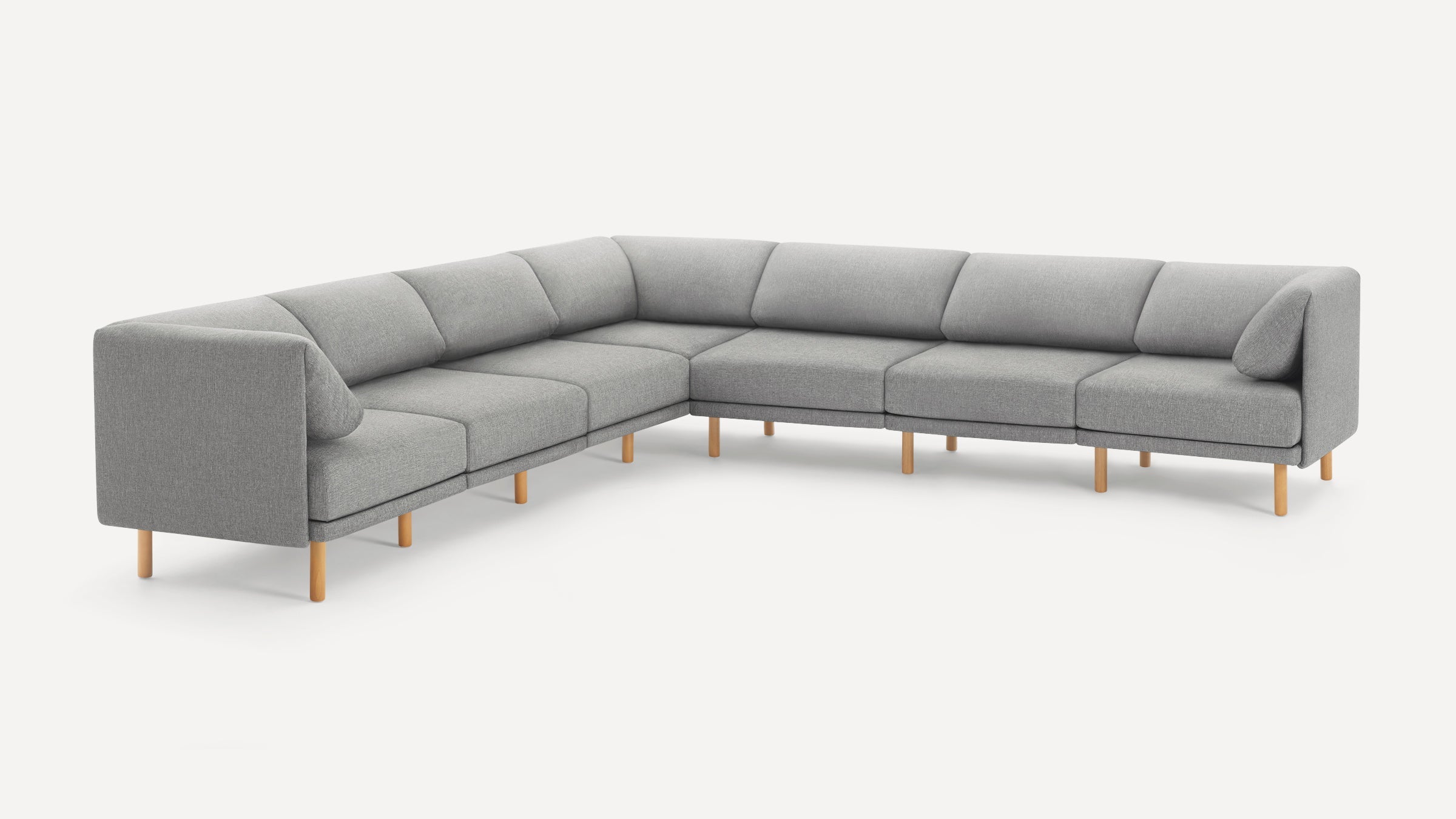Large L-shaped sectional sofa with light grey fabric upholstery and light wooden legs on a white background.